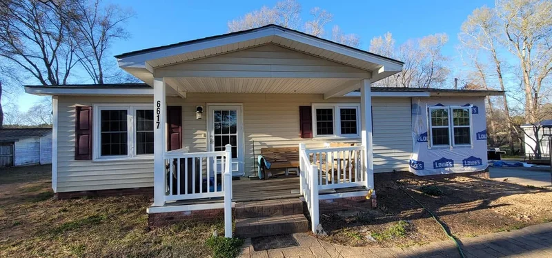 Cream vinyl-sided home with covered front porch during renovation