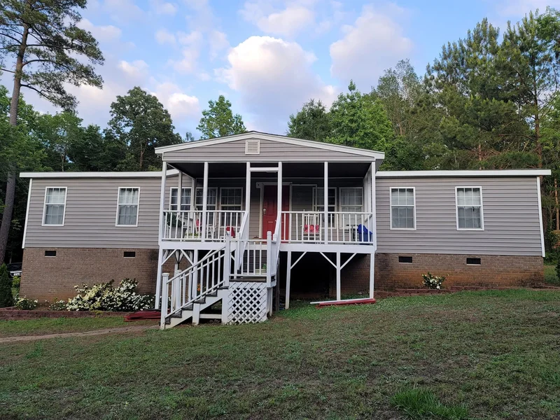 Gray manufactured home with brick skirting and front porch