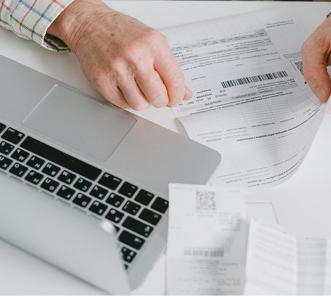 Someone working with a stack of invoices on their desk.