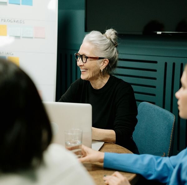 Woman sitting at an open laptop and smiling during a meeting.