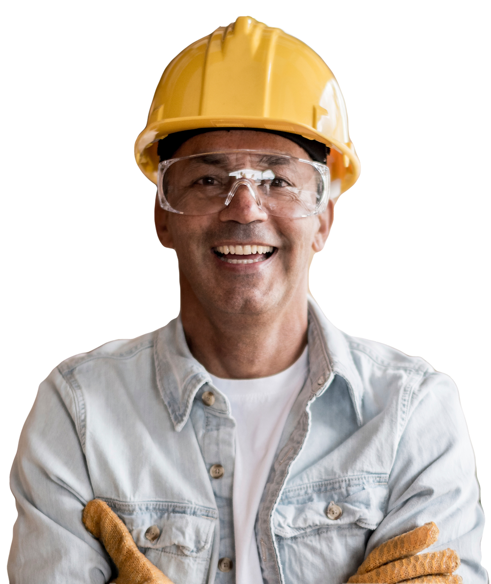 A smiling construction worker with their arms crossed over their chest, wearing a yellow hard hat and safety glasses.