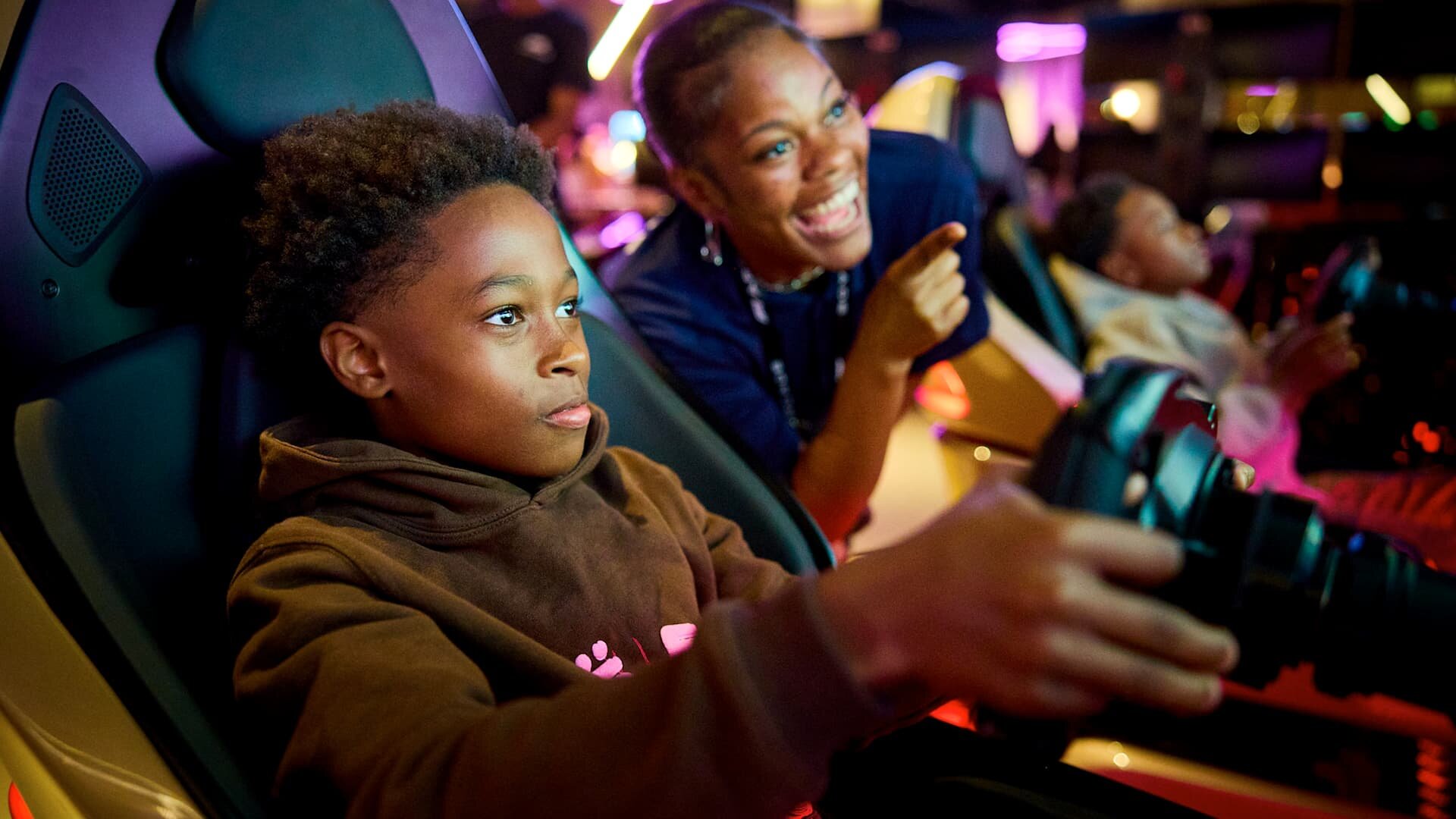 Child racing at F1 Arcade, guided by team member
