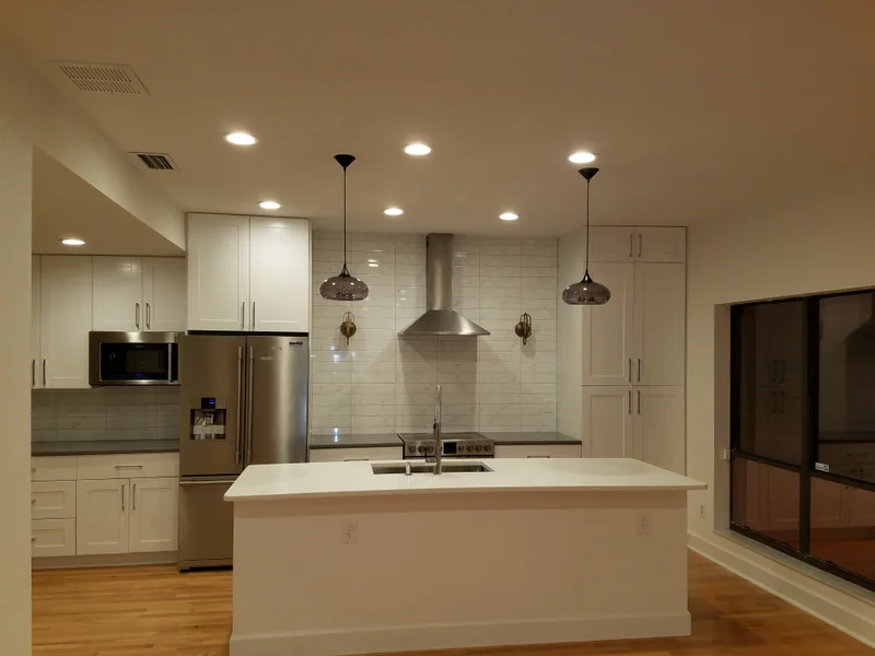 White kitchen remodel with island and stainless steel appliances