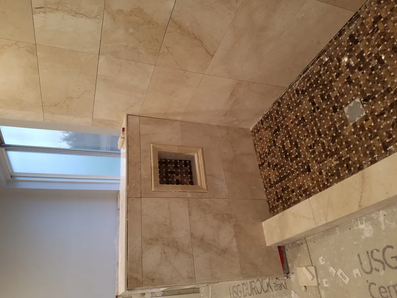 Tiled bathroom renovation with mosaic accent wall and niche