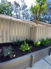 Fresh planting bed along a white privacy fence