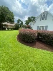 Shaped hedge bed bordering a white coastal home