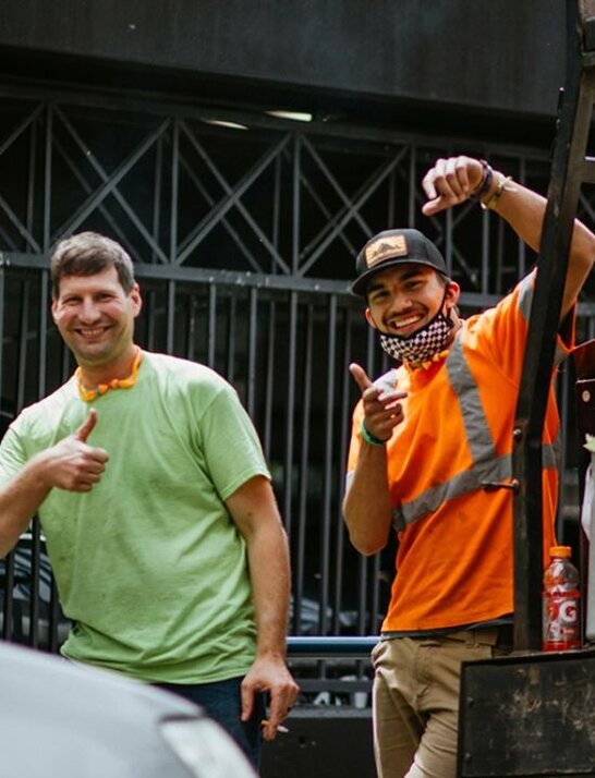 Two men stand alongside a truck, showcasing a casual and cooperative atmosphere.