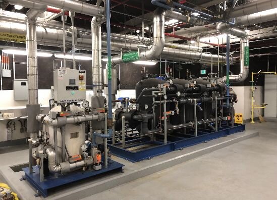 A large room featuring an array of pipes and industrial equipment, highlighting a mechanical workspace.
