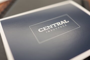 Close-up of a dark blue booklet cover with the words "CENTRAL INSURANCE" in white capital letters