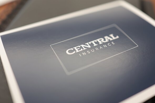 Close-up of a dark blue booklet cover with the words "CENTRAL INSURANCE" in white capital letters