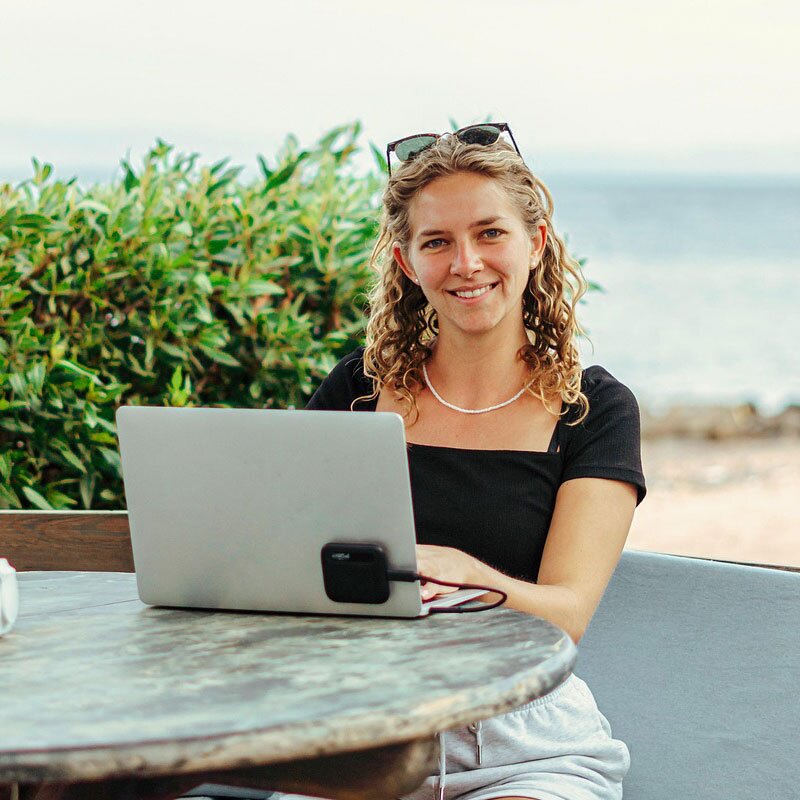 Woman sitting outdoors with a laptop.