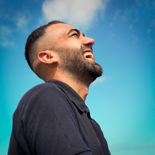 Man standing outside laughing.
