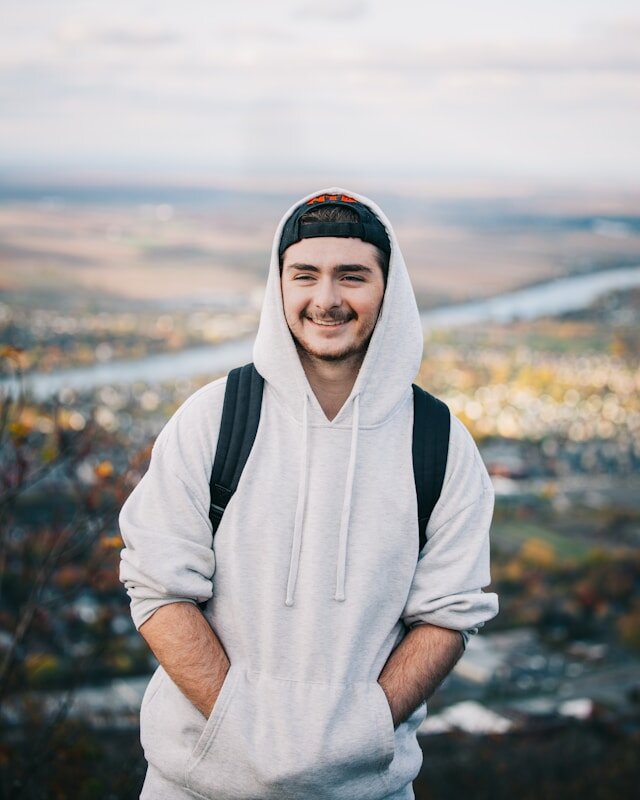 Man standing with hands in his hoodie pockets.