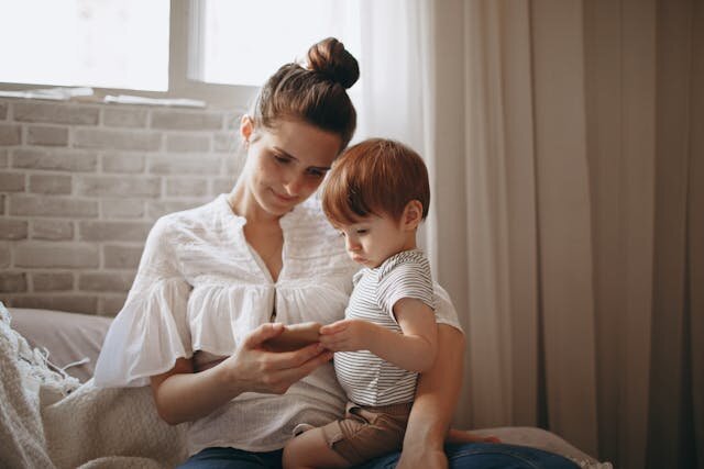 Young mother with her child reviewing a loan offer on her phone.