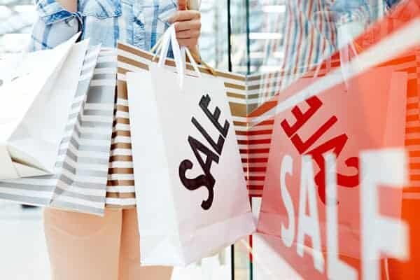 Woman-standing-holding-shopping-bags-written-sale