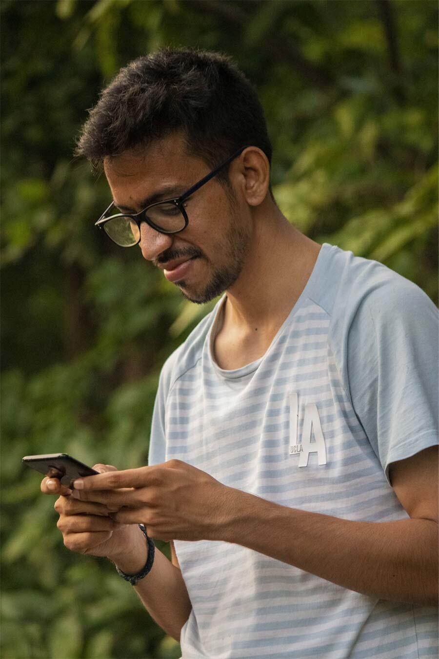 A man wearing black framed eyeglasses holding a smartphone 