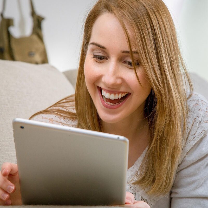 Woman lying on couch applying for an emergency home loan from a tablet