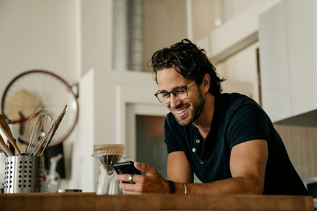 A happy man at a kitchen island using his phone