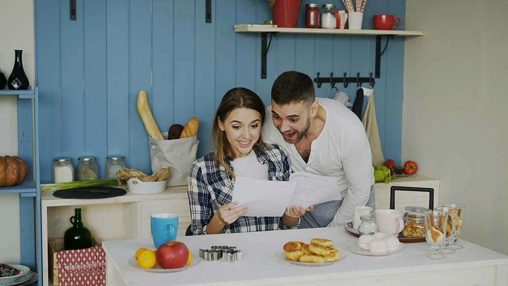 A young couple looking at papers in a small kitchen.