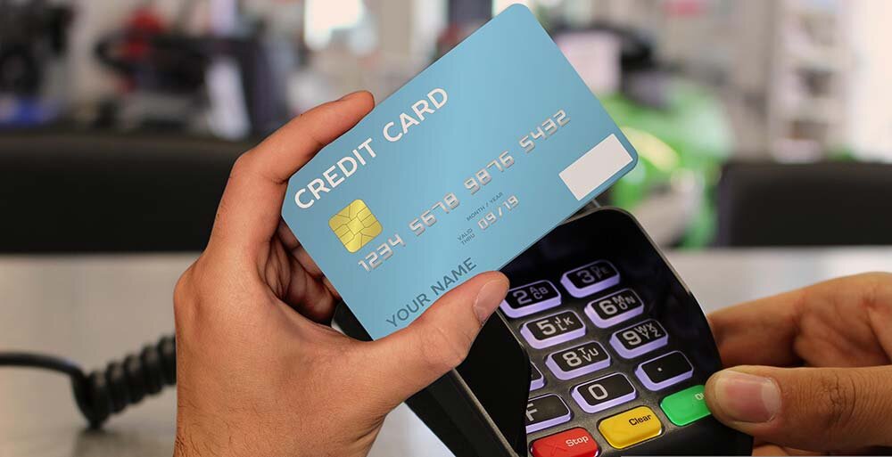 A person holding a dummy credit card and a card reader.
