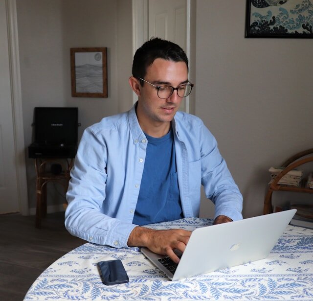 Man seated at a table using a laptop.