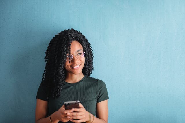 Smiling young woman holding a smartphone