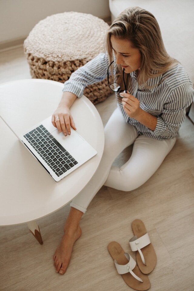 Lady seated on floor using a laptop on a coffee table to apply for an installment loan.