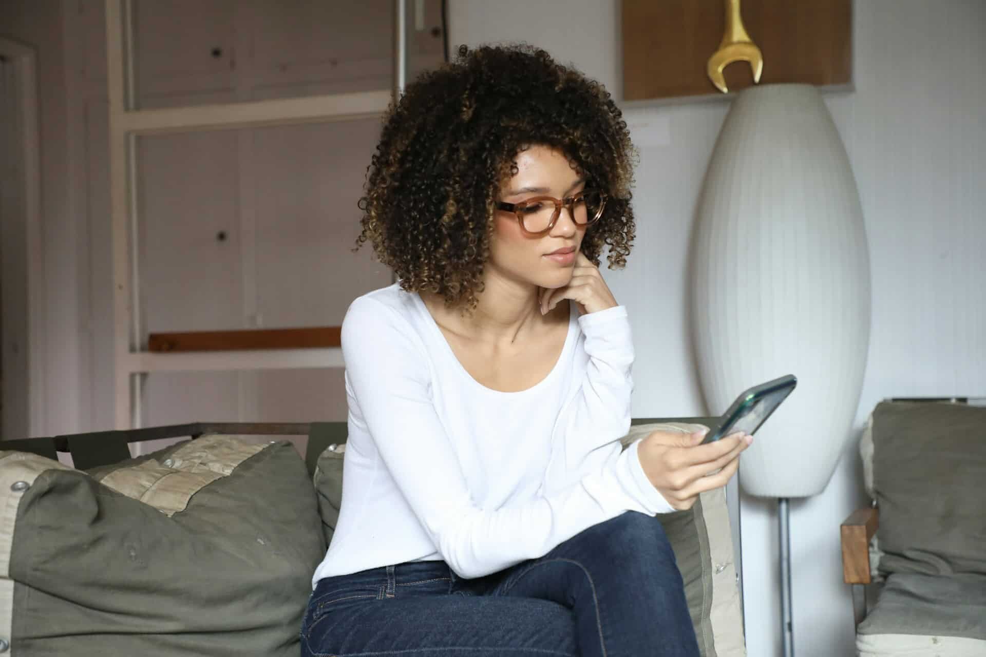 Woman looking down her phone while seated on bed