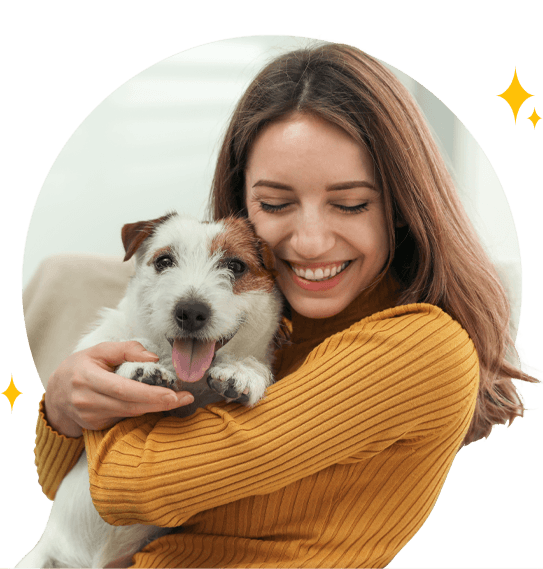 Woman sitting in a grass field holding white dog