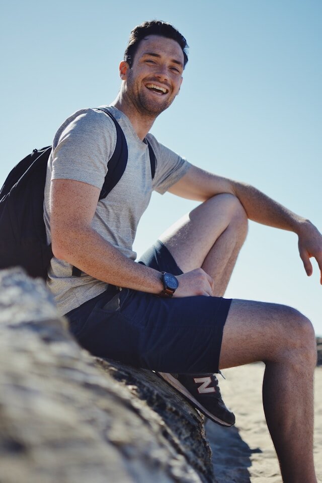Man carrying a backpack sitting on a rock.