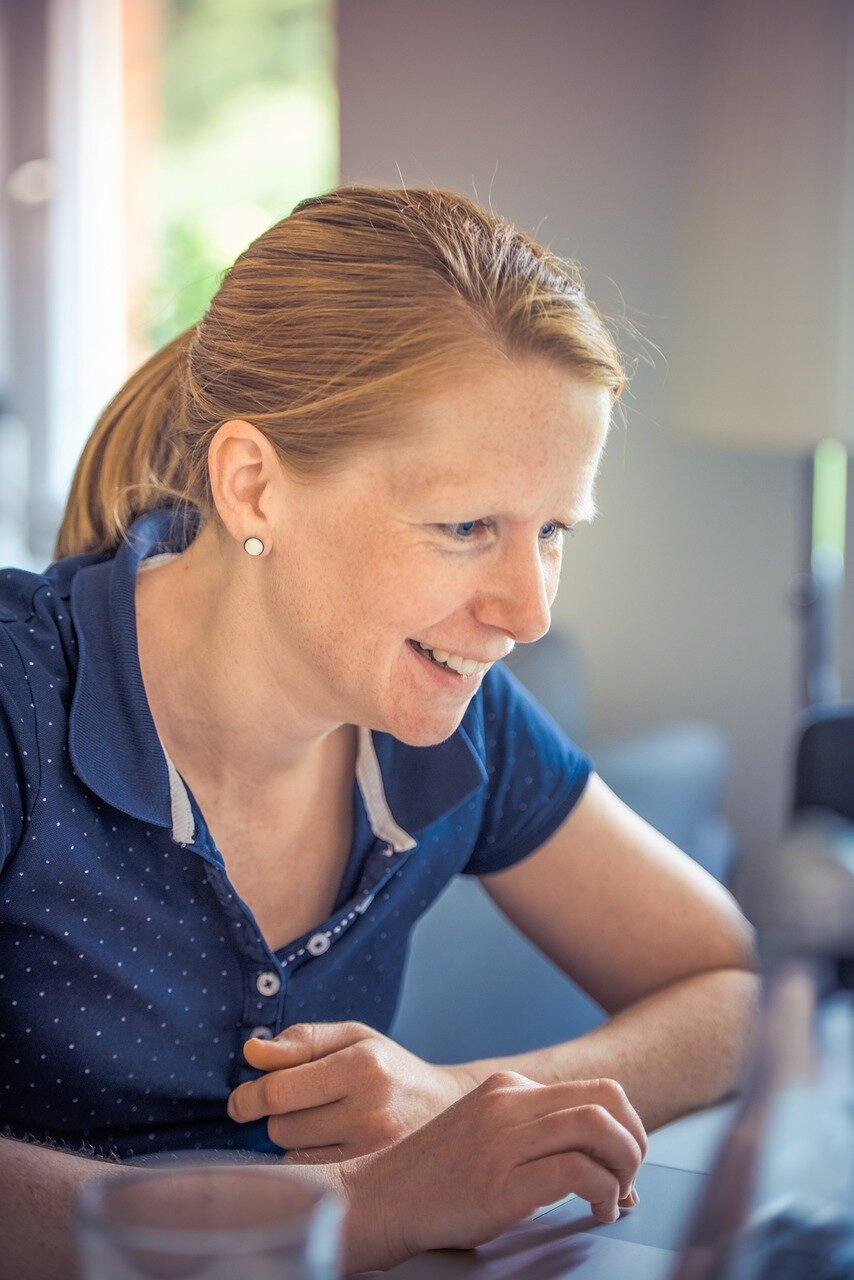 Smiling woman using notebook computer to learn about an Alabama line of credit.