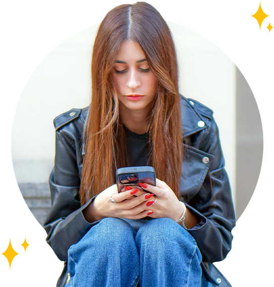 A worried young woman sitting on steps using a smartphone.