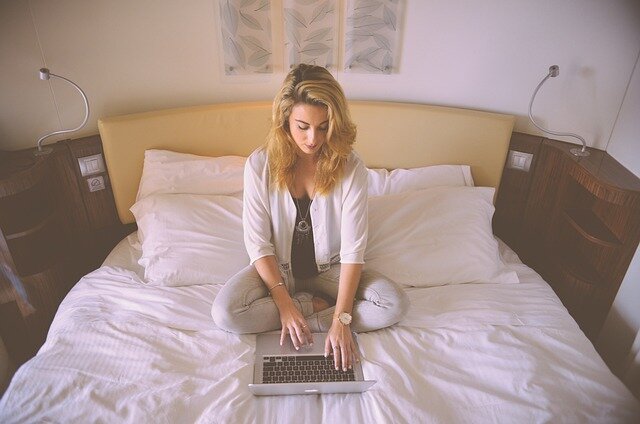 womanWoman sitting on a bed using a laptop computer-on-bed-with-laptop
