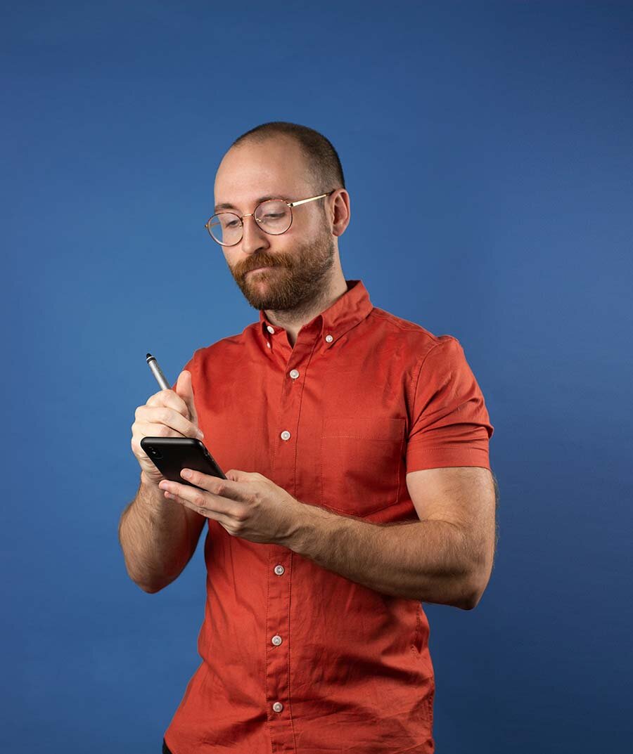 Man in a red shirt using an Apple Pencil to write on his phone