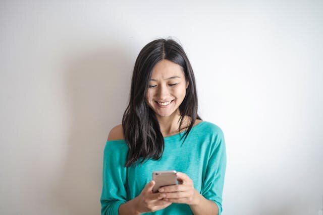 Smiling woman receiving notification of installment loan approval on her phone