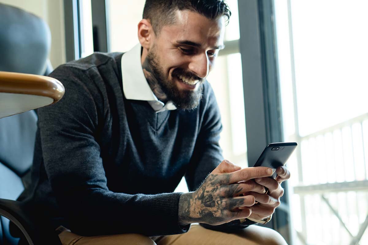 A happy man with a beard holding a cell phone