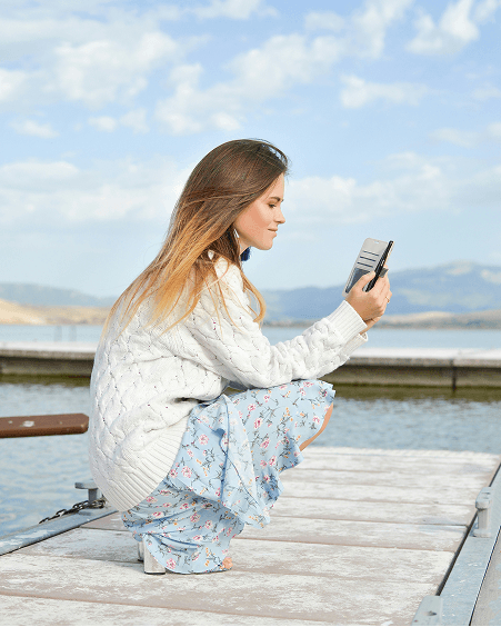 Woman squatting at a dock using a phone