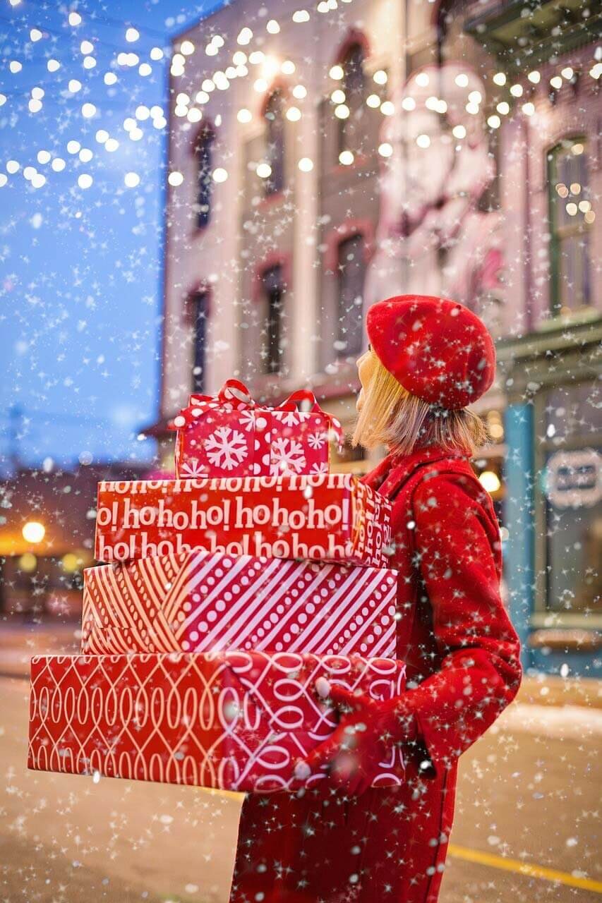 Woman in red carrying holiday gifts.