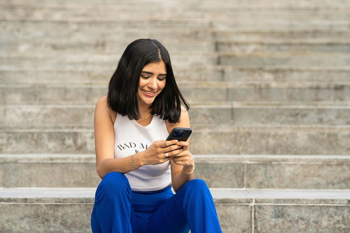 A young woman sitting on steps looking at her cell phone