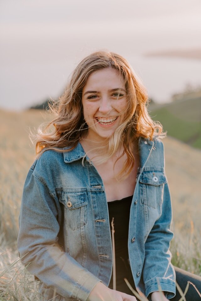 Woman seated in a grass field smiling