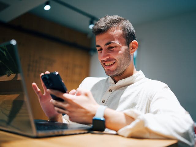 Smiling man receiving notification of personal loan approval on his phone