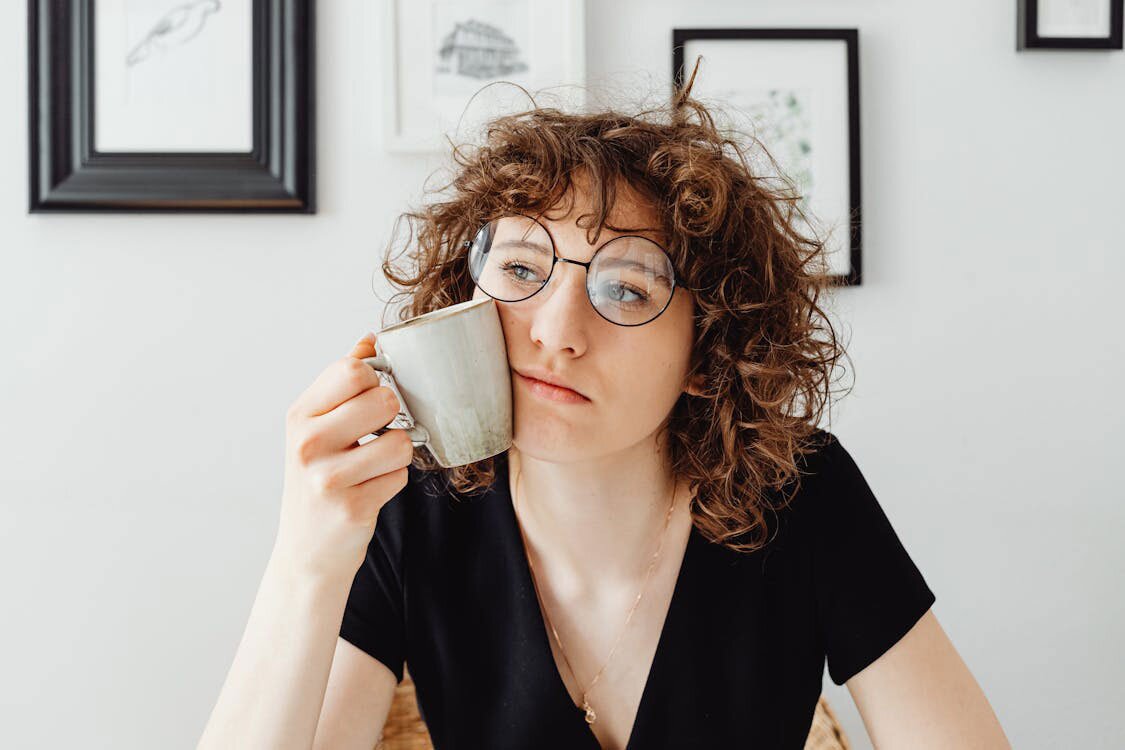 Young woman pressing a cup on her face while considering a credit card vs loan dilemma