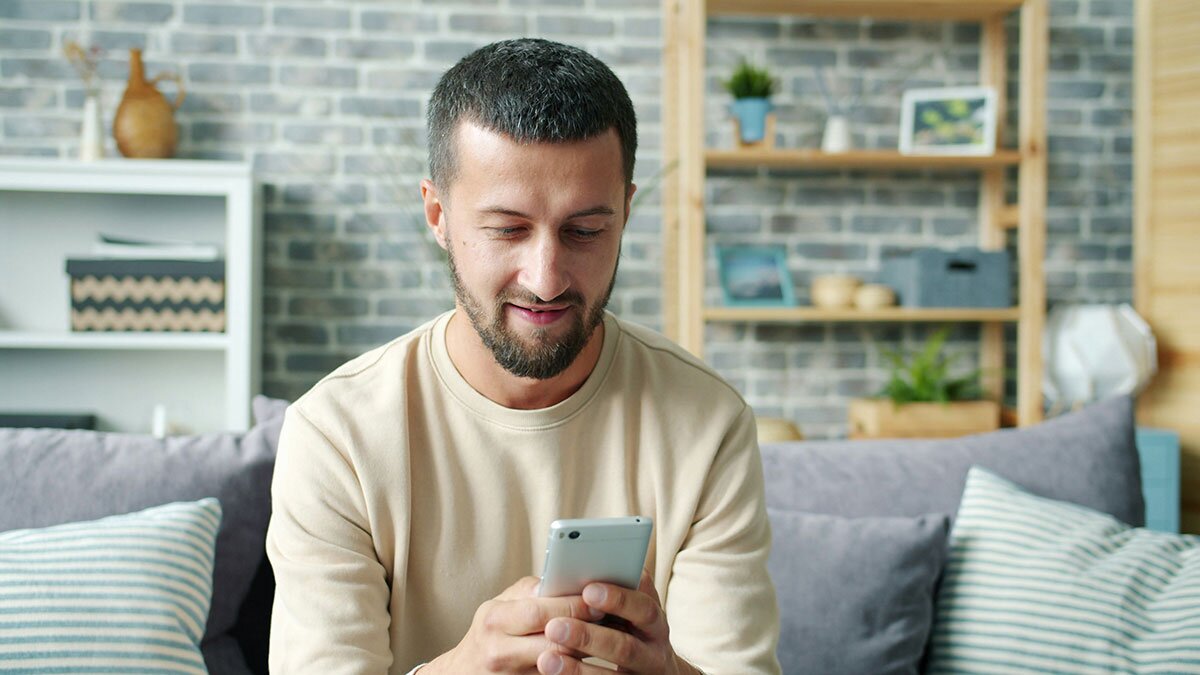 A young man sitting on a couch using a smartphone