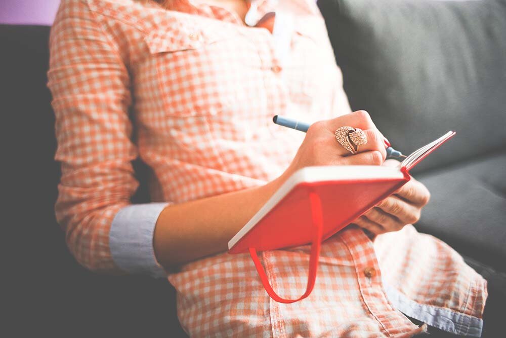 A woman sitting down writing in a notebook