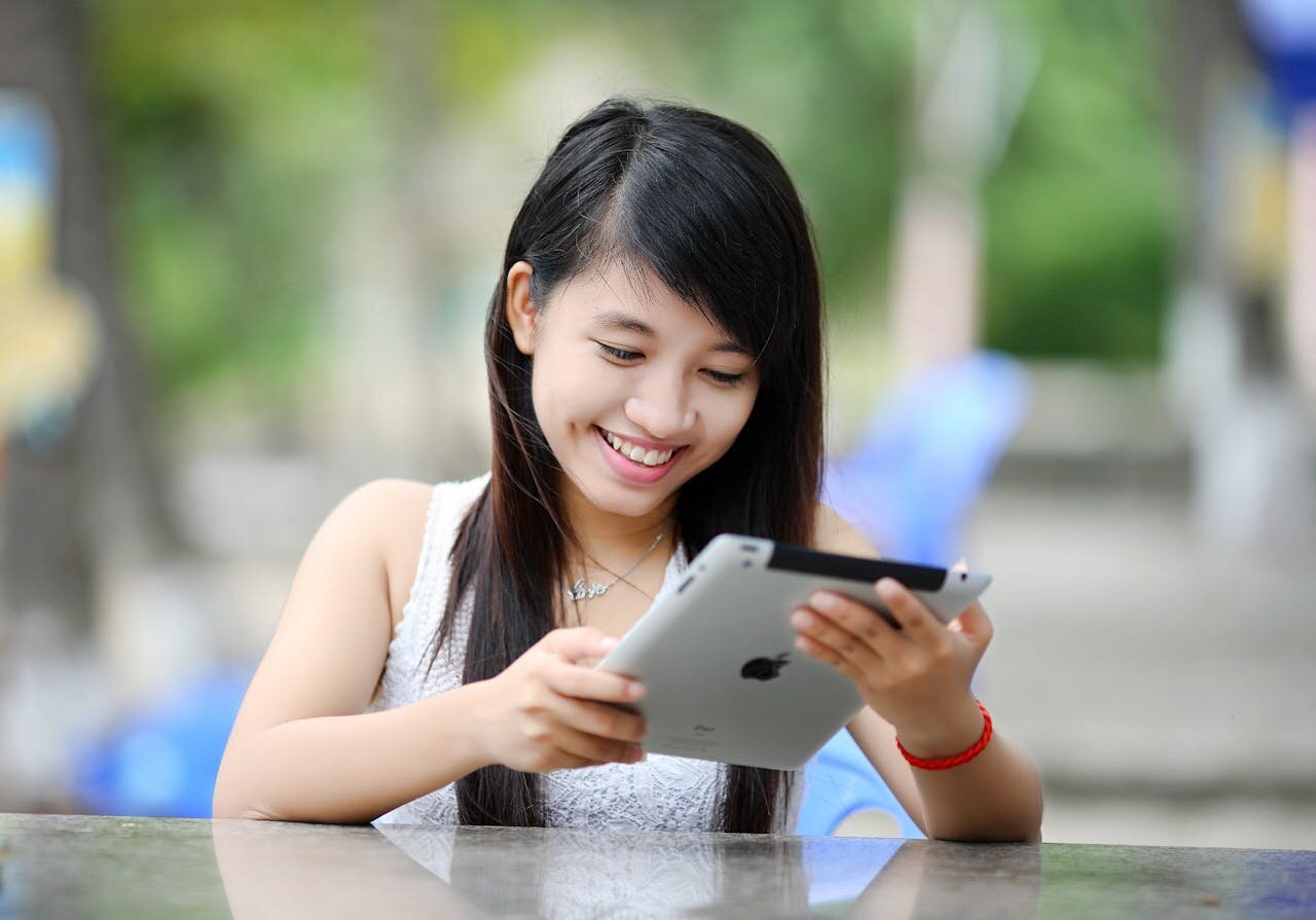 A young woman sitting at a table using a tablet computer.