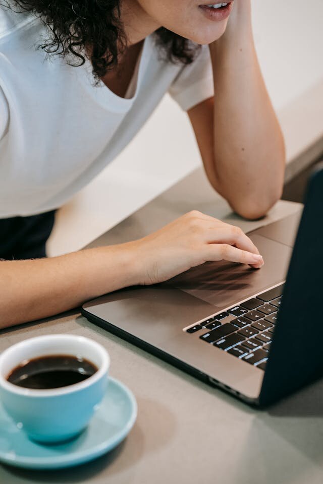 Woman with laptop and coffee reading about a line of credit.