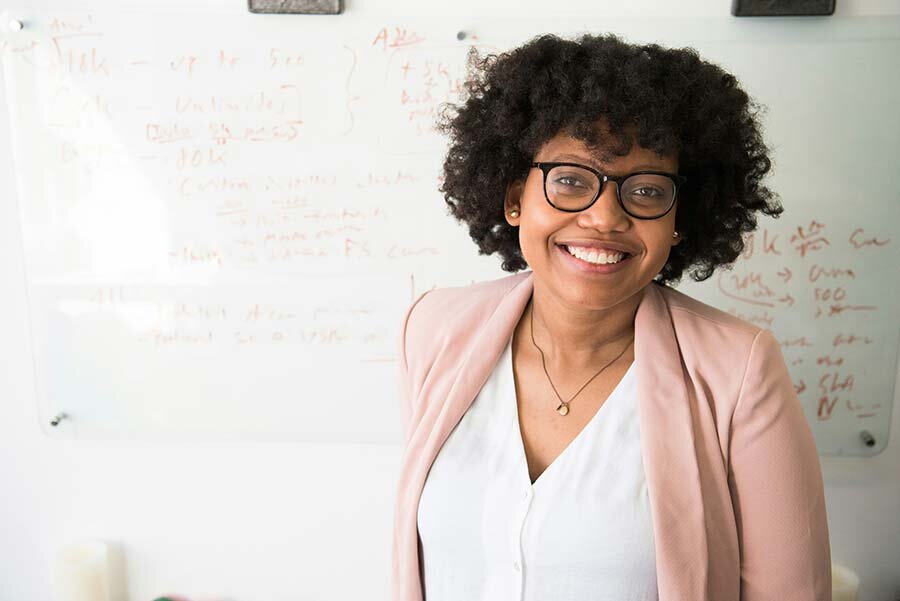A woman standing in front of a whiteboard smiling