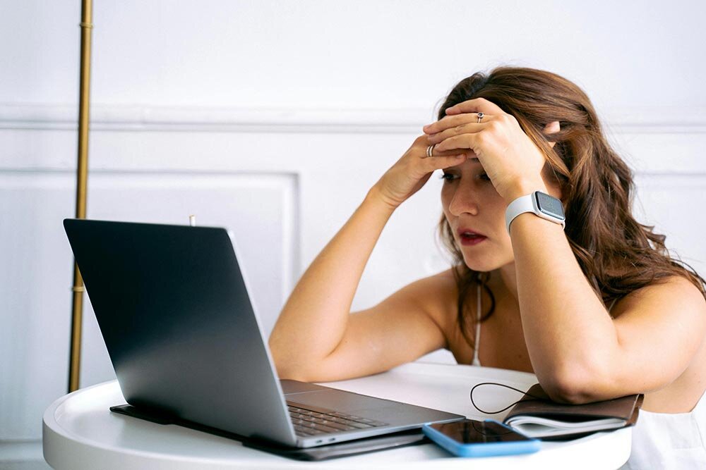 A young woman looking at a laptop trying to decide between loan options.