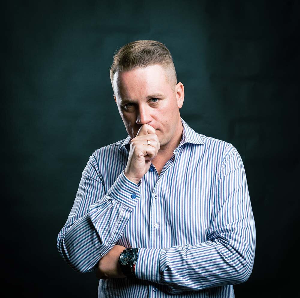 A worried man standing holding his hand to his mouth