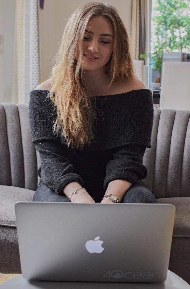 Woman sitting on a couch working from a laptop.